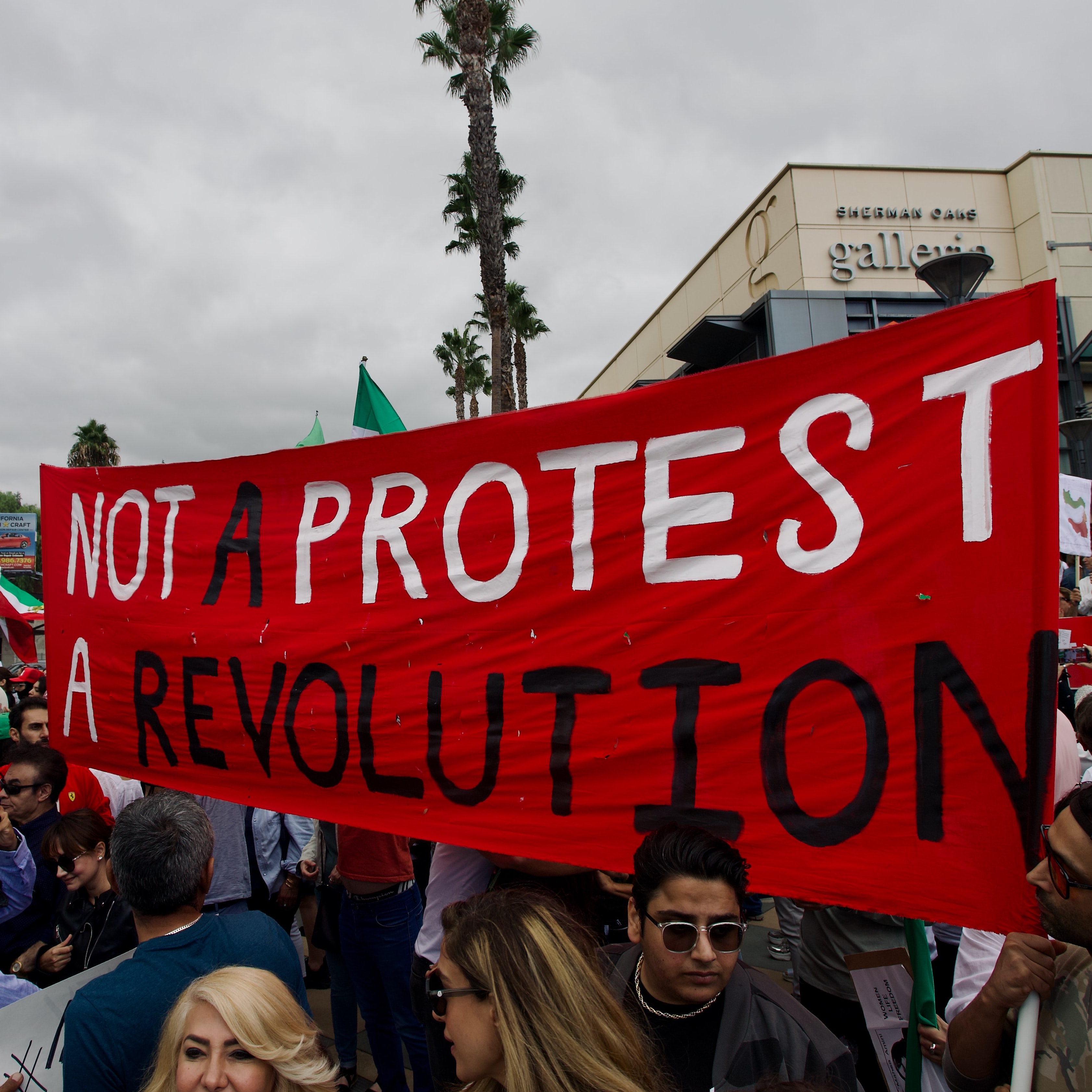 Photograph by Craig Melville, courtesy of Unsplash. Iran protest October 15, 2022 - Sherman Oaks, CA. Large red banner that says 'Not A Protest, A Revolution.